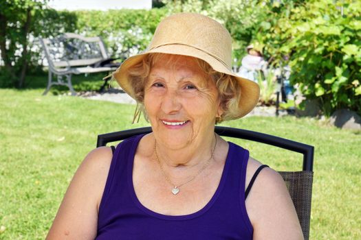 Senior woman with straw hat in the shade, enjoying summer