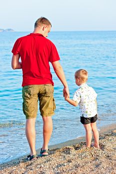 Father and son admiring the sea at sunset