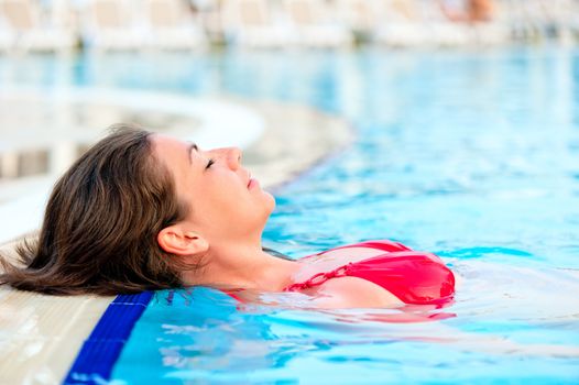 beautiful girl relaxes in the pool with your eyes closed