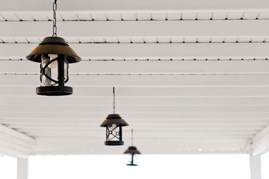 three metal lamps are suspended under the wooden white ceiling