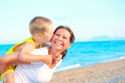 son kissing and hugging her mother on the background of the sea