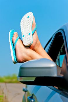 female legs dangling from the open car window in the shales