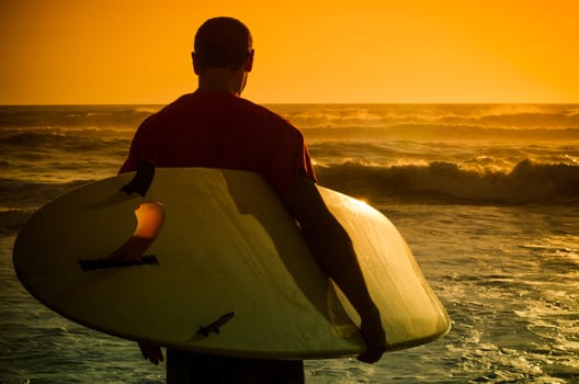 A surfer watching the waves at sunset in Portugal.