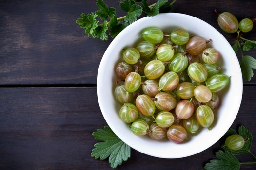 Green gooseberries in bowl on table background with copy space. Top view