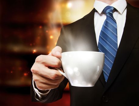 Business man holding a steaming cup of hot coffee