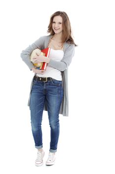 Happy young teenage student dressed in trendy casual clothes carrying her books under her arm, full length portrait on white