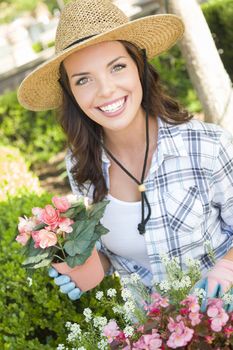 Attractive Happy Young Adult Woman Wearing Hat Gardening Outdoors.