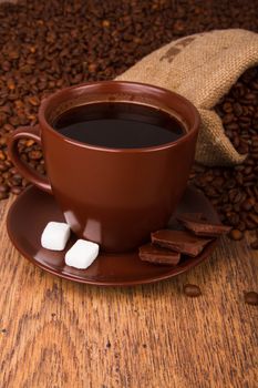 Cup of coffee and fresh coffee beans on a wooden background
