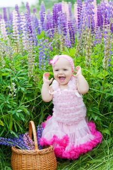 Little girl with a basket among blossoming lupines