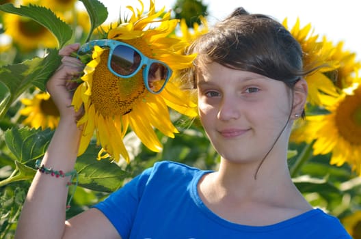 Young beautiful girl in a sunflower field with sunglasses