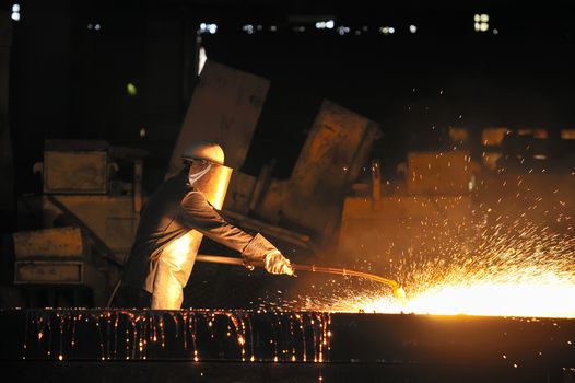 worker using torch cutter to cut through metal 