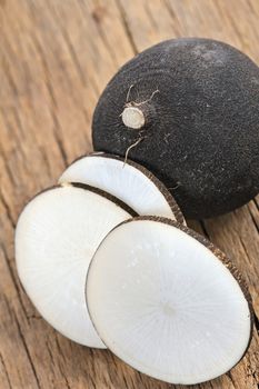 Black radish on a wooden board, whole and sliced