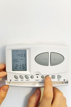 hand pressing button on digital thermostat