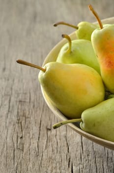 Fresh pears in bowl on wooden background