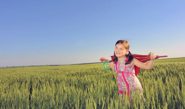 a little girl with a umbrella in green field