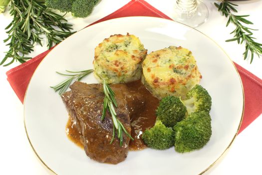 fried Venison medallions with potato gratin on a light background