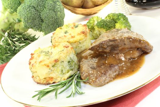 Venison medallions with potato gratin and broccoli on a light background