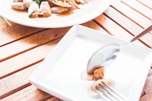 Spoon and fork on stir fried clams with roasted chili paste