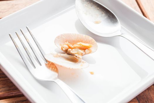 Stir fried roasted chili paste clam on white dish with spoon and fork