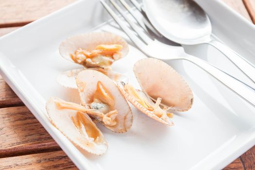 Stir fried roasted chili paste clams on white plate with spoon and fork