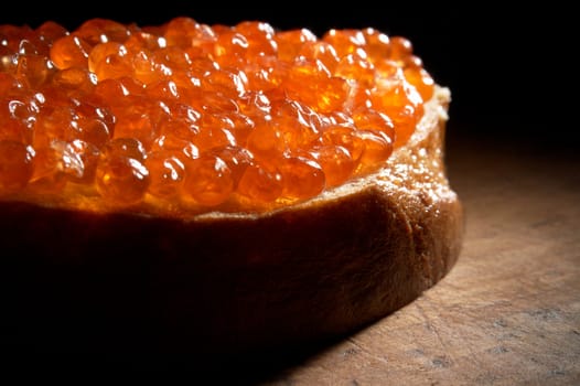  Sandwich with red caviar on a wooden table