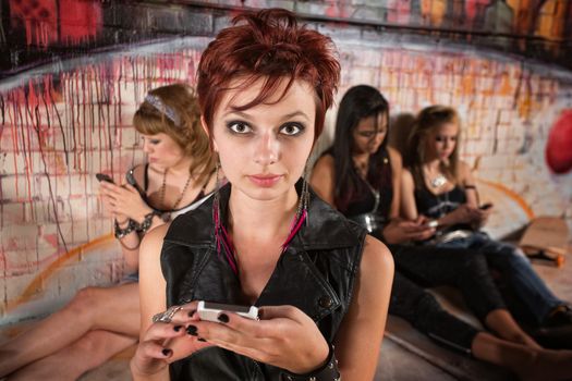 Serious young white female with phone near friends