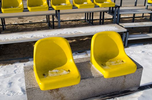 two yellow volleyball court plastic chairs on the cement platform