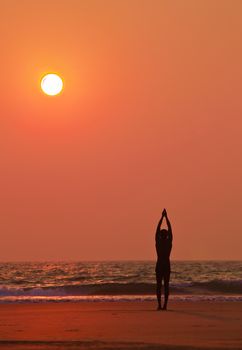 Yoga exercises at ocean sunset  Man s silhouette