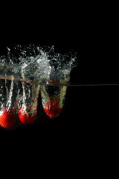 Colored red paprika in water splashes on black background