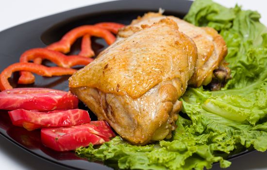 Tasty dish of roast chicken with vegetables on a black plate