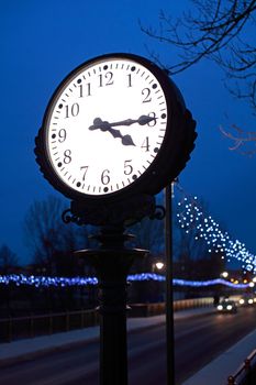 An iluminated clock in the night on the street
