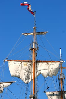 Masts and sails, old sailing ship on the sky background.