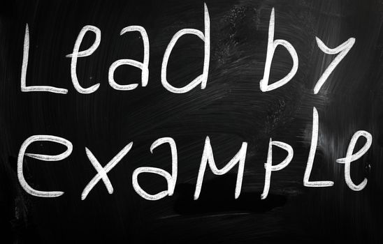 "Lead by example" handwritten with white chalk on a blackboard