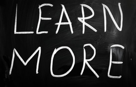 "Learn More" handwritten with white chalk on a blackboard