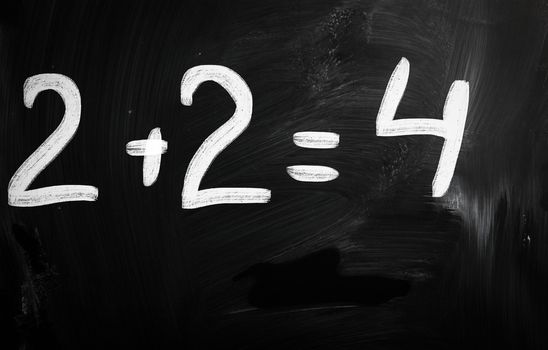 "2+2=4" handwritten with white chalk on a blackboard