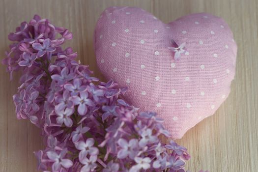 Textile heart polka dot next to a lilac on a wooden board