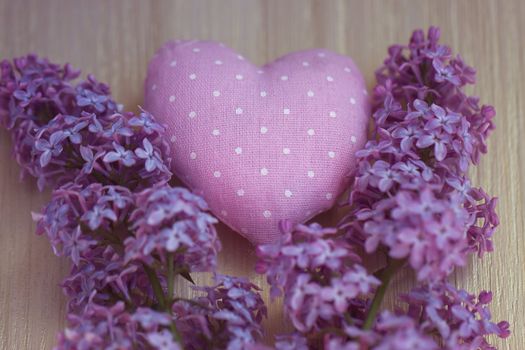 Textile heart polka dot next to a lilac on a wooden board