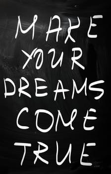 "Make your dreams come true" handwritten with white chalk on a blackboard