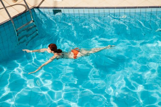 Young redhead woman in swimming pool 