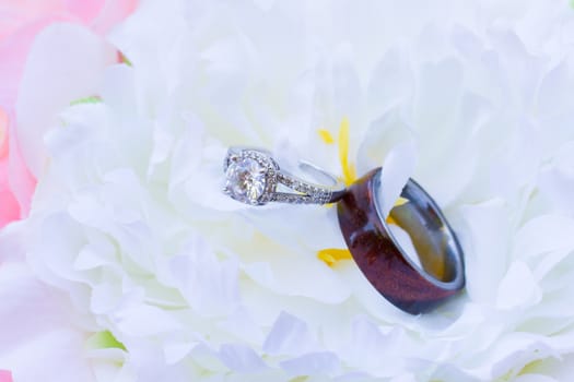 A bride and groom have their wedding rings photographed on some flowers from the bouquet.