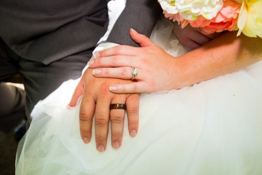 A bride and groom have their hands photographed on their wedding day to show off their wedding rings.
