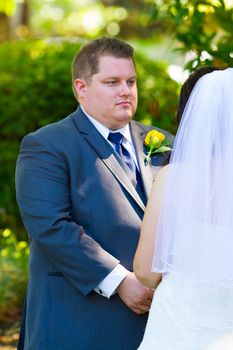 Vertical portrait of a groom during his vows at a ceremony on his wedding day.