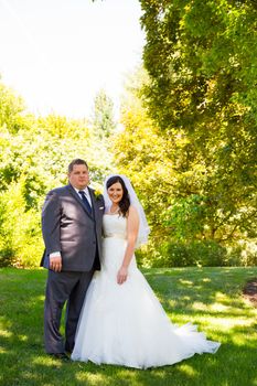 A beautiful bride and groom pose for portraits on their wedding day at a park outdoors.