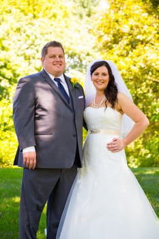 A beautiful bride and groom pose for portraits on their wedding day at a park outdoors.