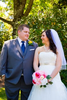 A beautiful bride and groom pose for portraits on their wedding day at a park outdoors.