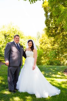 A beautiful bride and groom pose for portraits on their wedding day at a park outdoors.