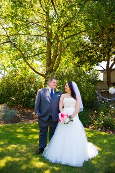 A beautiful bride and groom pose for portraits on their wedding day at a park outdoors.