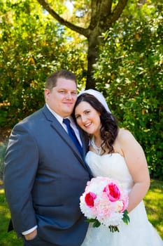 A beautiful bride and groom pose for portraits on their wedding day at a park outdoors.