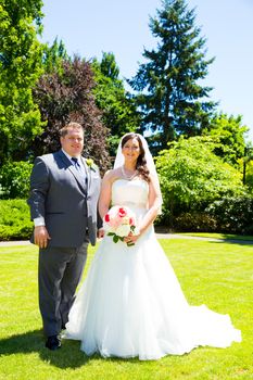 A beautiful bride and groom pose for portraits on their wedding day at a park outdoors.