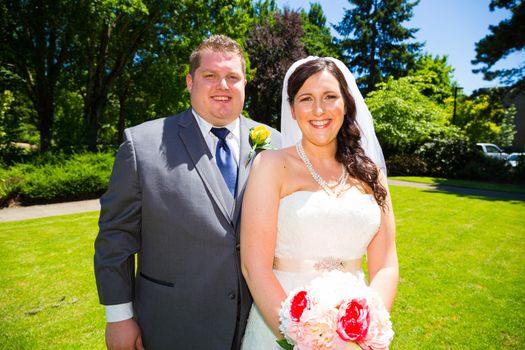 A beautiful bride and groom pose for portraits on their wedding day at a park outdoors.